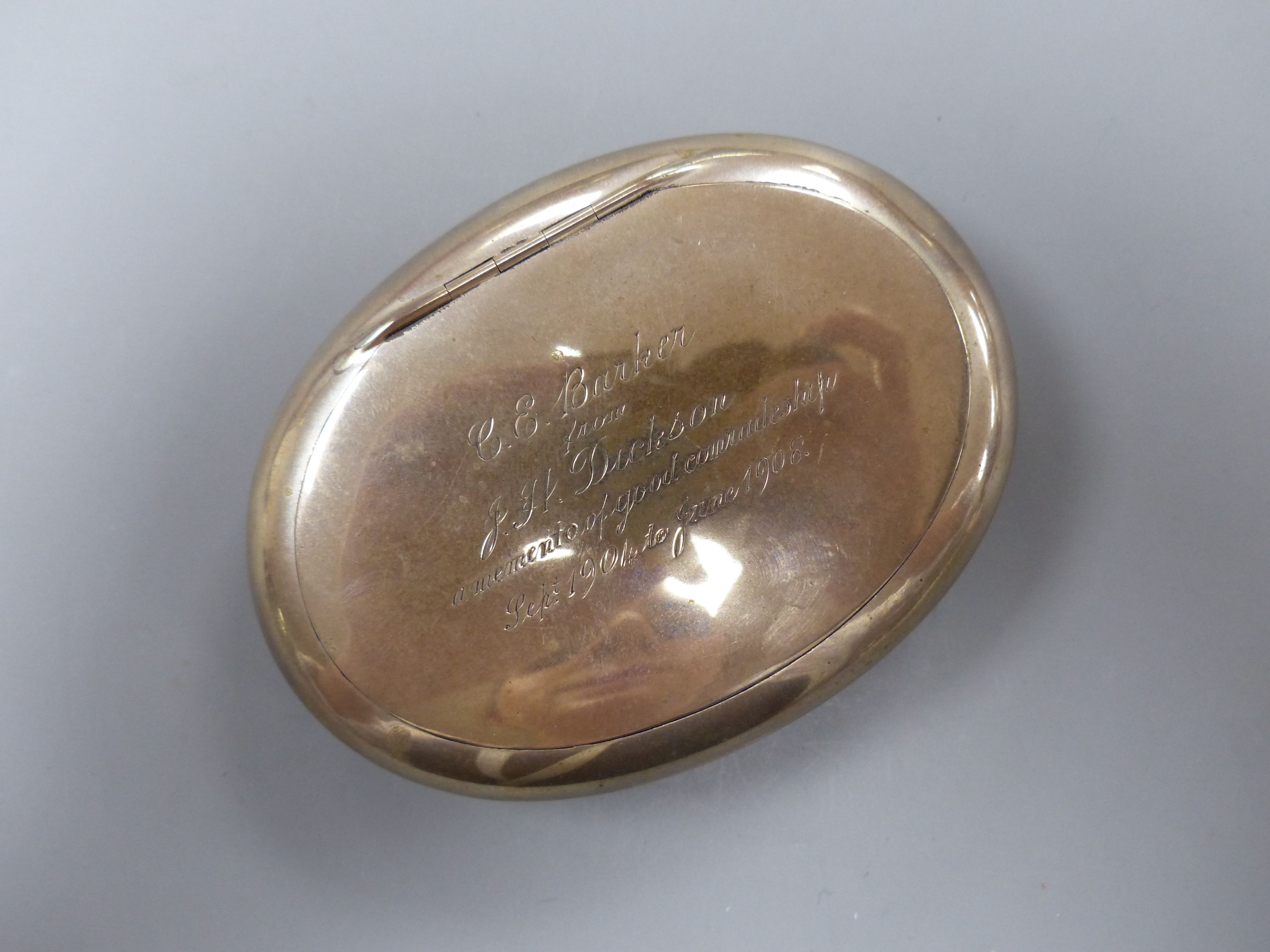 An Edwardian silver oval tobacco box, with engraved inscription, Chester, 1905, 9.7mm, 94 grams.